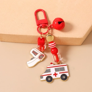 Detail of red bead keychain with ambulance and thermometer charms on a beige surface