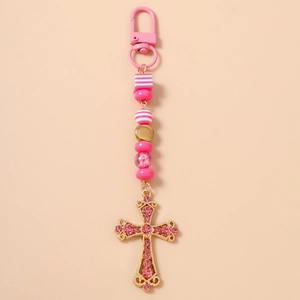 Détail du pendentif croix en strass rose avec perles rayées sur porte-clés doré