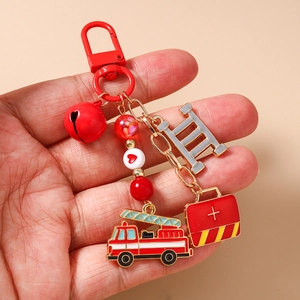 Detail of firefighter keychain with red fire truck, ladder and first aid kit charms