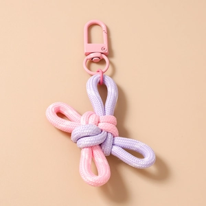 Detail of pink and purple woven knot keychain with a matte lobster clasp on neutral surface