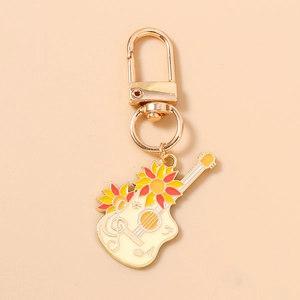 Vue détaillée d'un porte-clés guitare en émail avec motifs de tournesols et notes de musique
