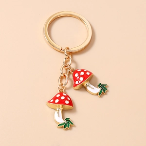 Detail of red spotted mushroom pendants with gold keychain ring and green leaf accents