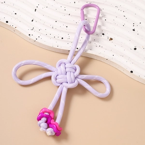 Close-up of a handmade purple braided knot keychain with pink wave details and metal clip