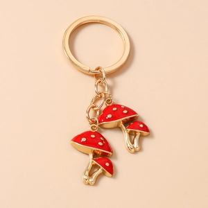 Close-up of golden mushroom keychain with red enamel dots and polished metal finish