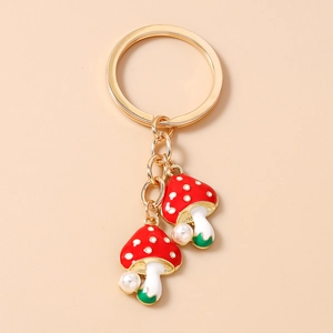 Detail view of red enamel mushroom keychain with white pearls and gold metal finish