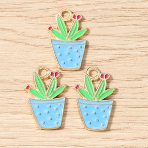 Flat lay detail of colorful enamel cactus charms on light wood texture background