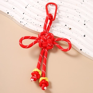 Macro detail of a traditional red Chinese knot keychain with floral charms and a metal clasp