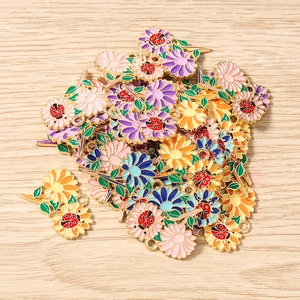 Dettaglio di ciondoli smaltati a fiori e coccinelle per la creazione di gioielli fai da te