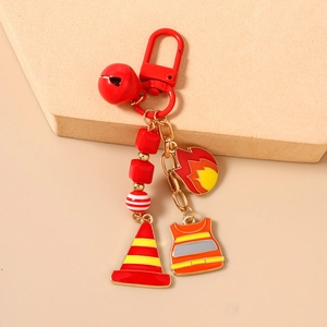 Detail of firefighter-themed keychain with fire cone, vest charms and red bell on stone