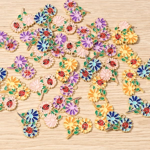 Dettaglio macro di ciondoli a fiori e coccinelle in smalto per creazione di gioielli