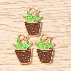 Detail of three enamel cactus charms with green leaves and pink buds for DIY jewelry