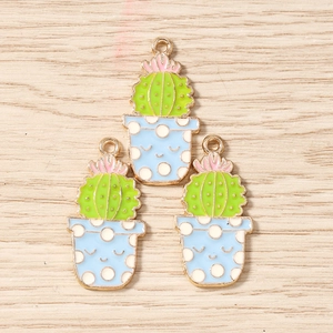 Vue détaillée de trois pendentifs cactus en émail avec fleurs roses et visages souriants