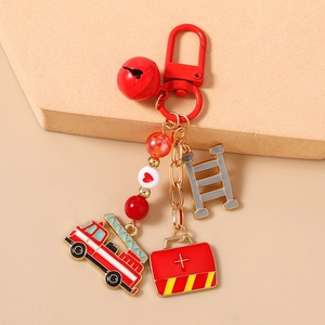 Detail of firefighter keychain with red fire truck and first aid kit charms