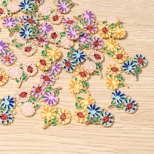 Dettaglio dei ciondoli a fiore e coccinella in smalto per la creazione di gioielli