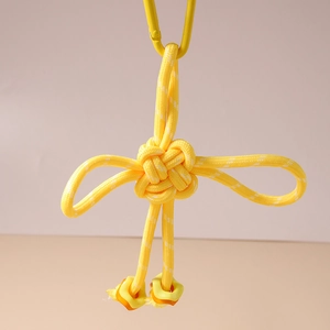 Detail of handcrafted yellow braided Chinese knot keychain with resin charms and D-ring buckle