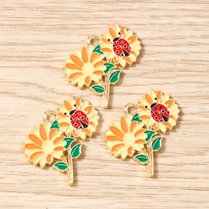 Dettaglio di ciondoli in lega a forma di girasole e coccinella per la creazione di gioielli
