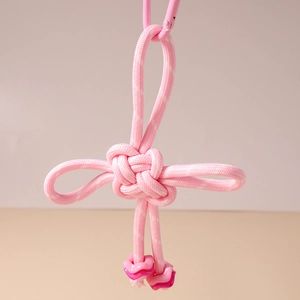 Detailed view of pink woven knot charm with metallic carabiner and heart beads