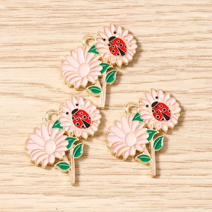 Dettaglio macro di ciondoli a margherita rosa con coccinella per creazione gioielli
