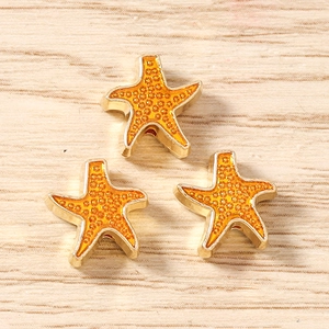 Dettaglio di tre ciondoli a forma di stella marina arancione con base dorata per DIY