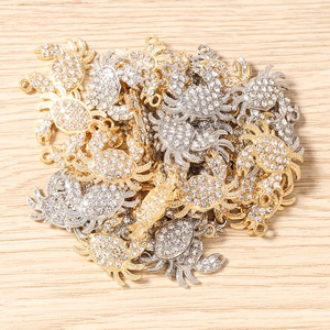 Détail macro de breloques crabe en strass plaqué or et argent pour création de bijoux