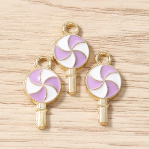 Détail macro de 3 breloques sucettes violettes et blanches avec monture dorée pour bijoux
