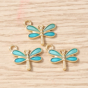 Détail de trois breloques libellules avec émail bleu dégradé et cadres dorés en alliage métal