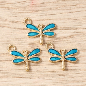 Trois pendentifs libellule en émail bleu ciel avec monture dorée sur fond bois clair