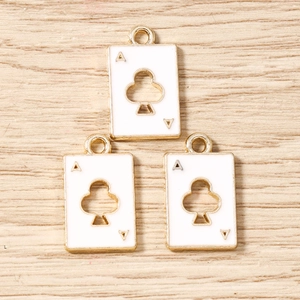 Detailed close-up of three gold-plated enamel Ace of Clubs poker card charms on wood