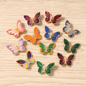 Colorful enamel butterfly pendants with gold alloy edges on a wooden background