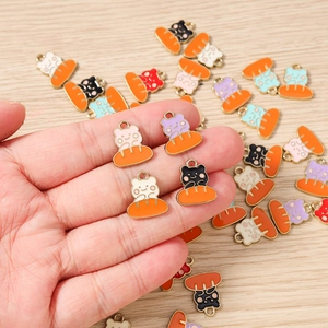 Dettaglio di simpatici ciondoli gatto su pane in smalto per gioielli DIY e accessori fatti a mano