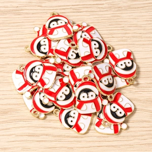 Detail von Pinguin-Anhängern mit roten Schals für DIY-Schmuck auf Holzoberfläche