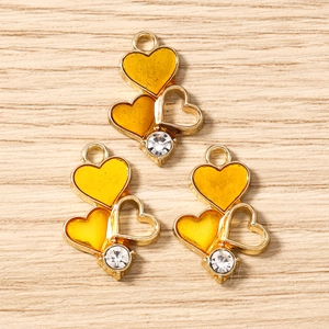 Detail of DIY heart charms featuring yellow resin fills and clear zircon on wood background