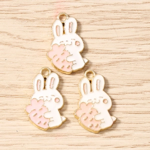 Detailed view of three white rabbit enamel charms with pink carrots for DIY jewelry making