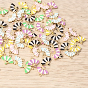 Detail view of colorful enamel fan pendants for DIY jewelry making on wooden surface