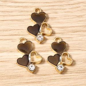 Macro detail of triple heart charms with black enamel and gold frame for DIY jewelry making