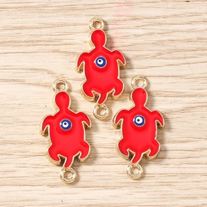Detail of red turtle jewelry pendants with blue evil eye motifs for DIY crafts