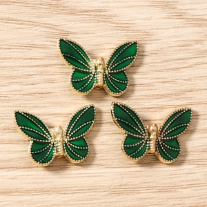 Macro shot of dark green enamel butterfly charms with gold metal filigree details