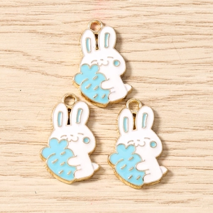 Detail of three cute rabbit alloy charms with blue carrots for DIY jewelry making