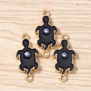 Detail of three golden turtle charms with black enamel and evil eye motif on wood