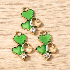 Detailed macro of golden heart pendants with green enamel and crystal for DIY jewelry