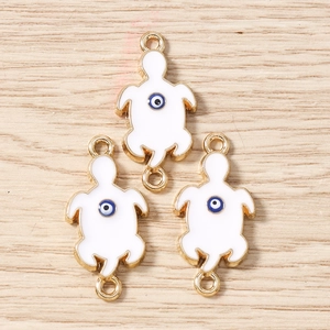 Detailed view of three gold turtle evil eye charms for jewelry making on wood background