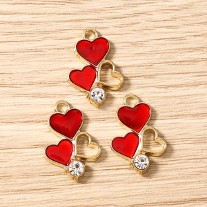 Detailed macro view of red enamel heart charms with gold frames and zircon stones