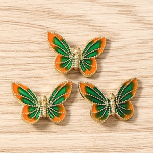 Detail of three colorful butterfly charms with enamel wings and golden alloy borders