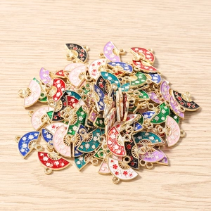 Detailed close-up of colorful enamel fan pendants with flower patterns on wood surface
