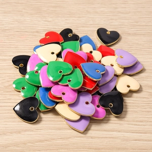 Colorful heart-shaped enamel pendants in various colors on a light wood background