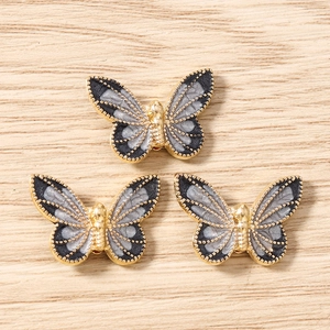 Detailed view of alloy butterfly pendants with grey marble texture on wooden background