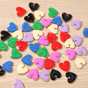 Macro view of colorful heart-shaped enamel charms with gold alloy edges on wood surface