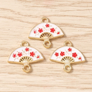 Close-up of three fan-shaped enamel flower pendants with gold plating for jewelry making