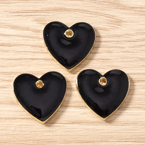 Detailed view of three heart-shaped black enamel alloy pendants for DIY jewelry making