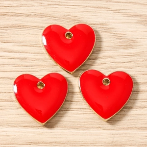 Detailed view of three red enamel heart charms with gold finish for DIY jewelry crafting